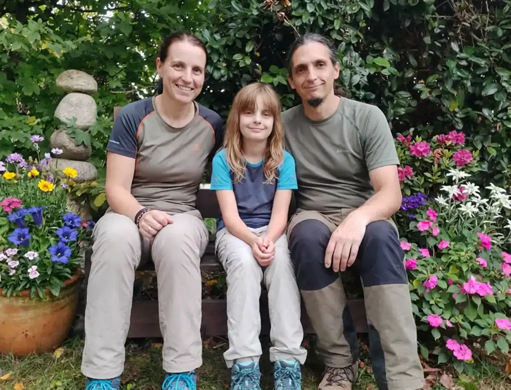 Famille Grandhaye souriante assise sur un banc dans un jardin au vieux four en été